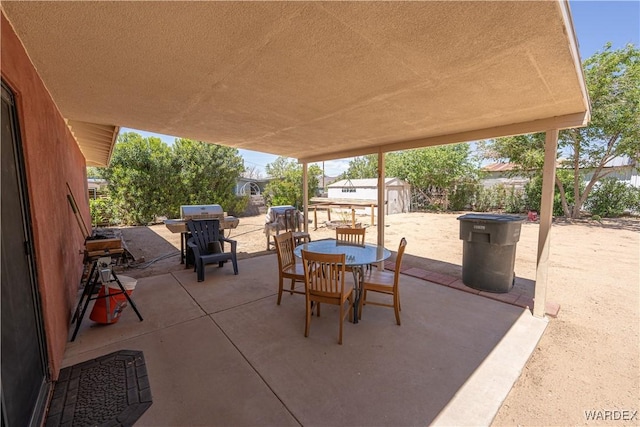 view of patio featuring fence, a storage unit, an outbuilding, and outdoor dining space
