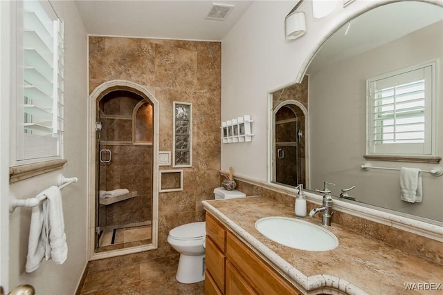 full bathroom featuring vanity, toilet, visible vents, and a stall shower