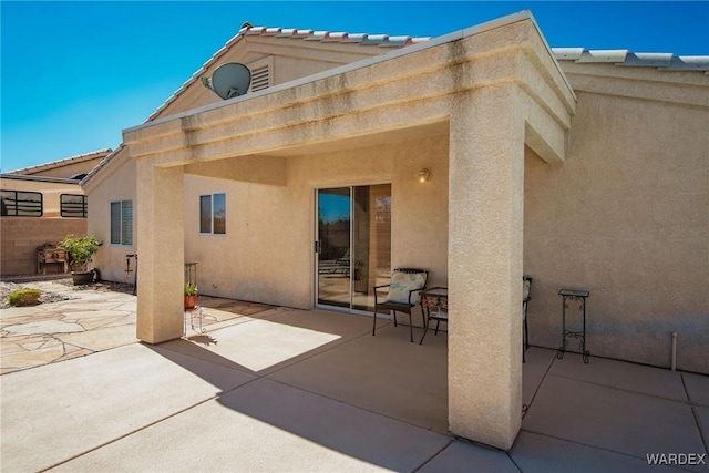 back of property with a patio area, stucco siding, and a tiled roof