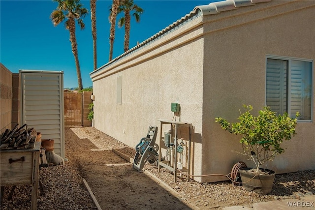 view of side of property with fence and stucco siding