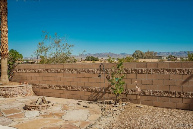 view of yard with a patio area, a mountain view, an outdoor fire pit, and a fenced backyard