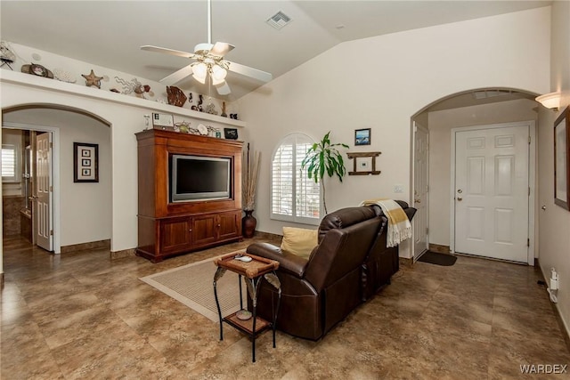 living area featuring visible vents, arched walkways, baseboards, ceiling fan, and vaulted ceiling