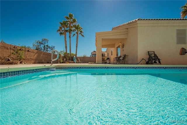 outdoor pool featuring a water slide and fence