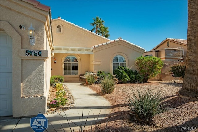 mediterranean / spanish-style house featuring stucco siding, a garage, and a tiled roof