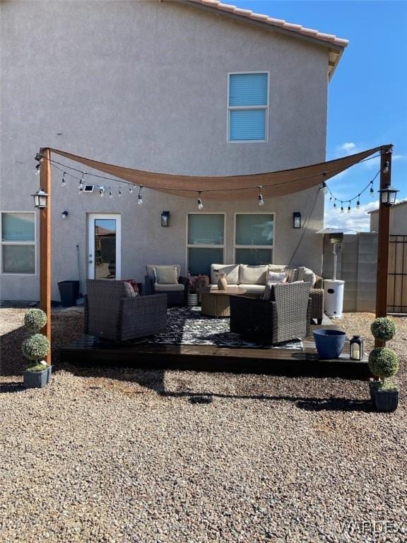 rear view of house featuring an outdoor hangout area, fence, and stucco siding