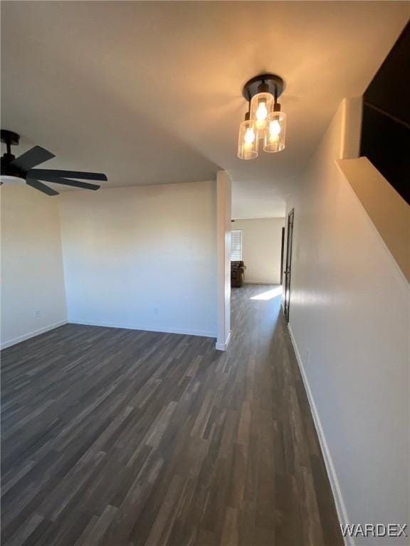 interior space featuring baseboards, a ceiling fan, and dark wood-style flooring