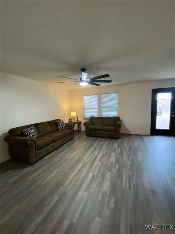 living room featuring baseboards, ceiling fan, and wood finished floors