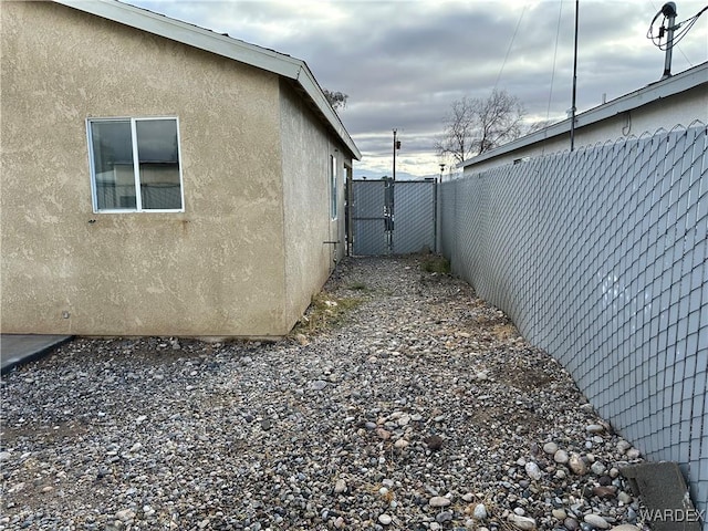 view of home's exterior featuring a gate, fence, and stucco siding