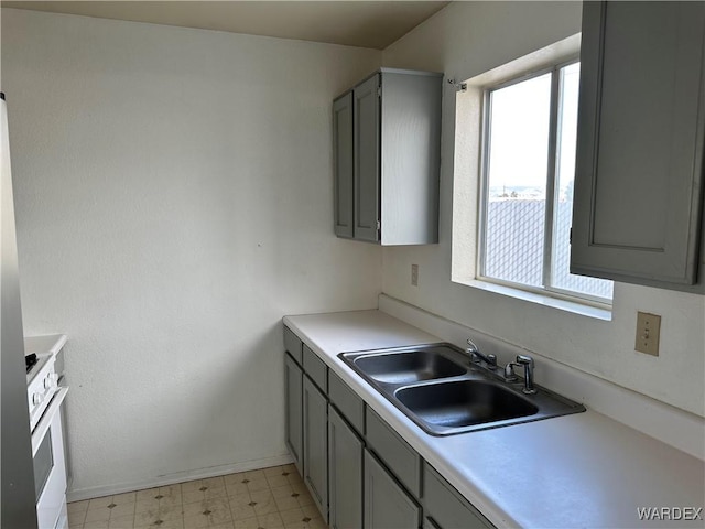 kitchen featuring gray cabinets, light countertops, a sink, and light floors