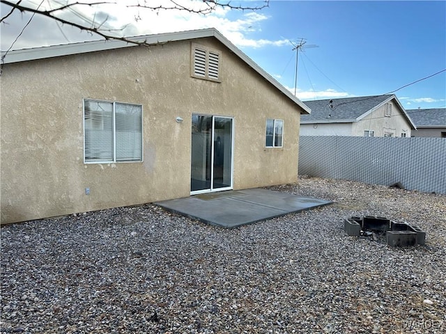 rear view of house with a patio area, fence, and stucco siding