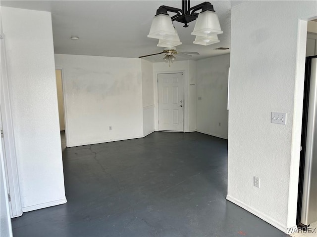 spare room with concrete flooring, visible vents, a textured wall, and a ceiling fan