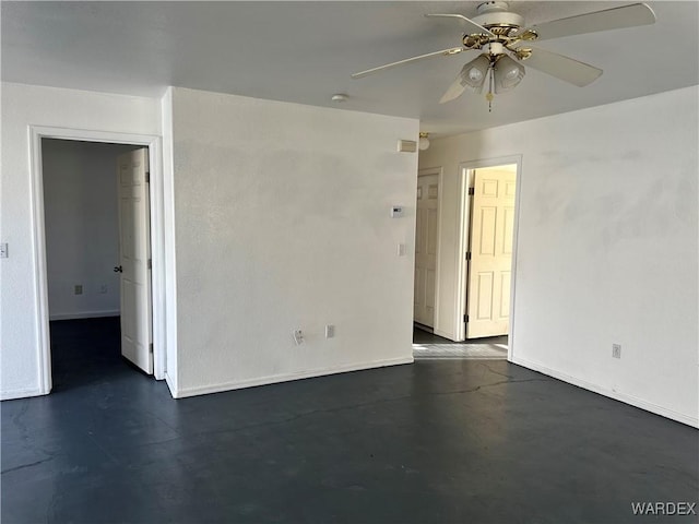 empty room featuring concrete floors, baseboards, and a ceiling fan