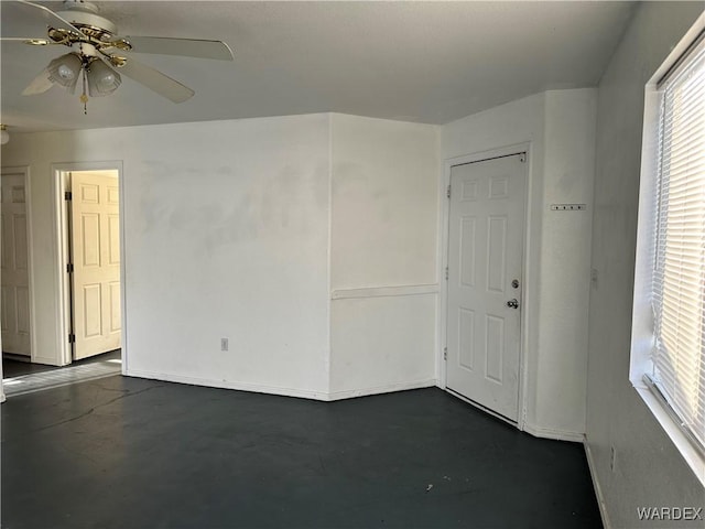 empty room with ceiling fan and concrete flooring