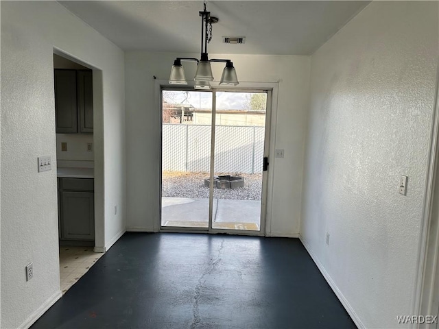 unfurnished dining area featuring concrete flooring, a textured wall, visible vents, and baseboards