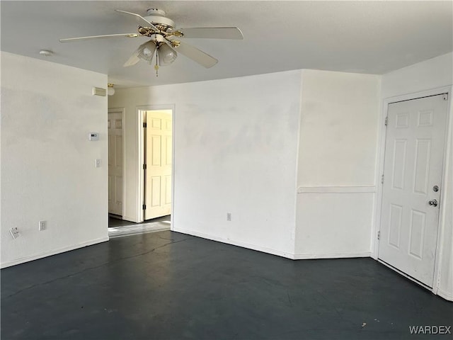 spare room with a ceiling fan, concrete flooring, and baseboards