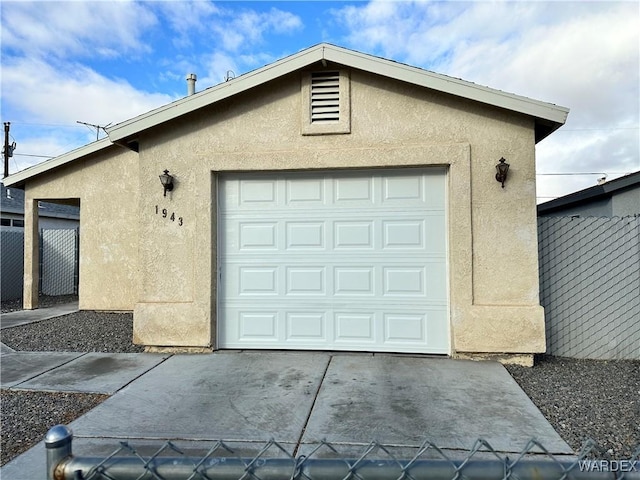 garage featuring concrete driveway and fence