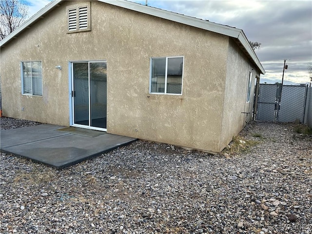 back of property featuring a patio, fence, a gate, and stucco siding