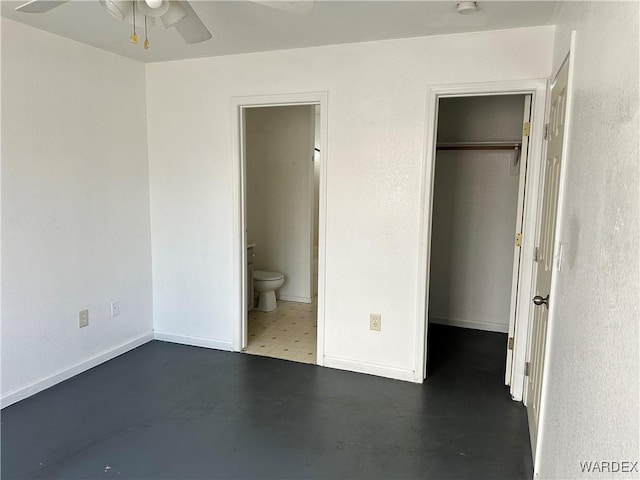 unfurnished bedroom featuring concrete floors, baseboards, a closet, a walk in closet, and ensuite bath