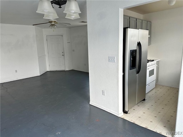 kitchen with a ceiling fan, light countertops, gray cabinets, white gas range, and stainless steel fridge