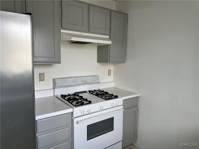 kitchen with gray cabinets, white range with gas stovetop, light countertops, and under cabinet range hood