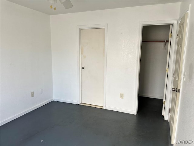 unfurnished bedroom with finished concrete floors, a closet, and baseboards