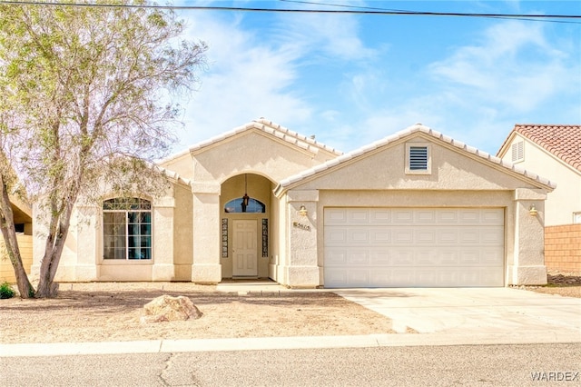 mediterranean / spanish-style home featuring concrete driveway, a tiled roof, an attached garage, and stucco siding