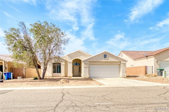 mediterranean / spanish-style house with driveway, a tile roof, an attached garage, fence, and stucco siding