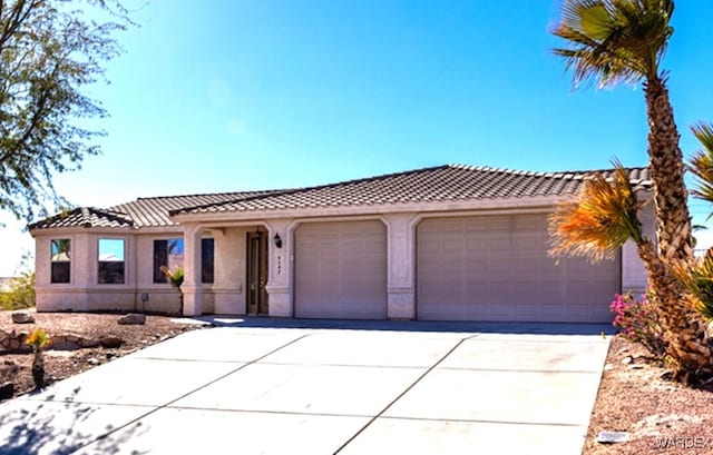 4049 S Cassidy Dr, Fort Mohave, AZ 86426 - view of front of property with a garage, a tile roof, concrete driveway, and stucco siding