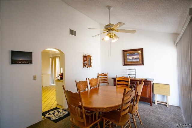dining area with ceiling fan, arched walkways, a textured ceiling, visible vents, and carpet flooring