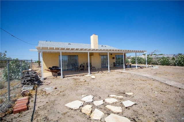 back of property featuring a pergola, a patio area, a chimney, fence, and stucco siding