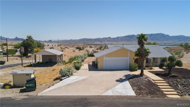 ranch-style house with a garage, a mountain view, driveway, and stucco siding