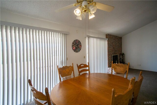 carpeted dining room with a textured ceiling, ceiling fan, and a brick fireplace