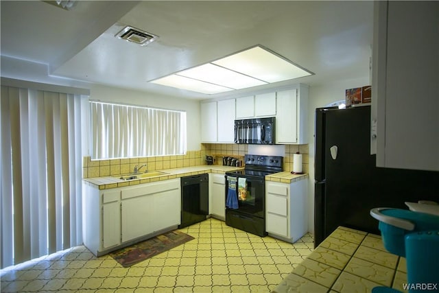 kitchen with visible vents, a sink, tile counters, black appliances, and white cabinetry