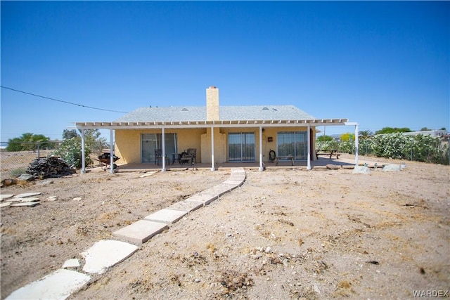rear view of property featuring a patio area, stucco siding, fence, and a chimney