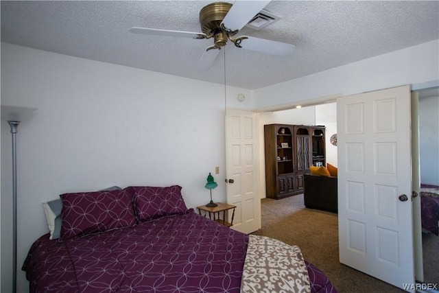 carpeted bedroom with visible vents, a textured ceiling, and ceiling fan