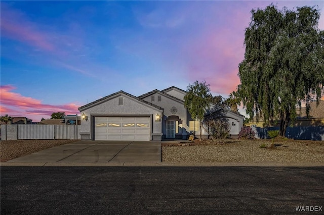 ranch-style house featuring a garage, driveway, fence, and stucco siding