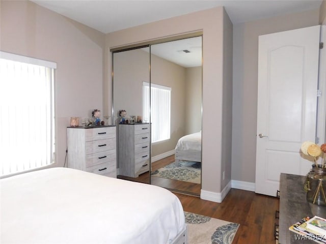 bedroom featuring a closet, baseboards, visible vents, and dark wood-style floors