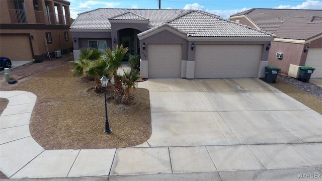 ranch-style home with stucco siding, an attached garage, a tile roof, and concrete driveway