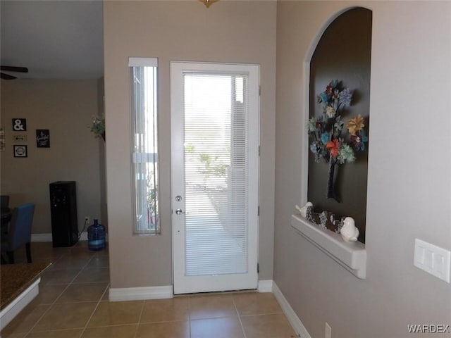 entryway featuring light tile patterned floors, a ceiling fan, and baseboards