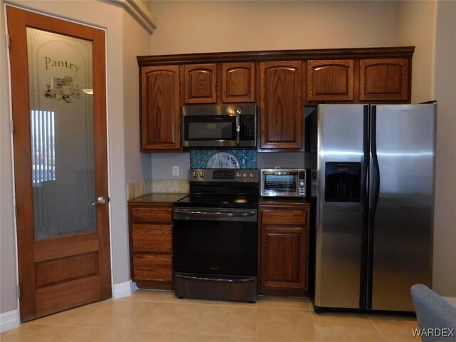 kitchen with light tile patterned floors, brown cabinets, dishwasher, and a sink