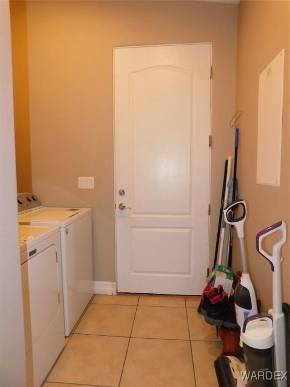 clothes washing area featuring light tile patterned flooring, cabinet space, baseboards, and washer and clothes dryer