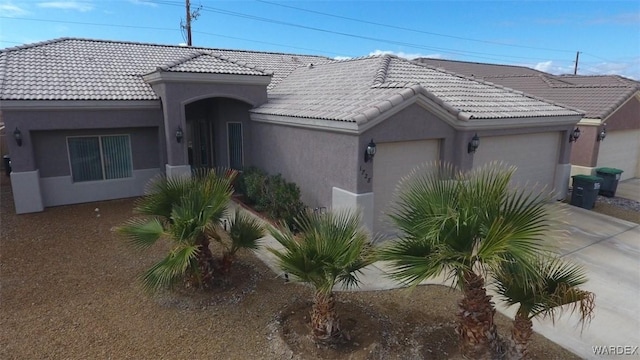 view of front of property with a tiled roof, stucco siding, an attached garage, and concrete driveway