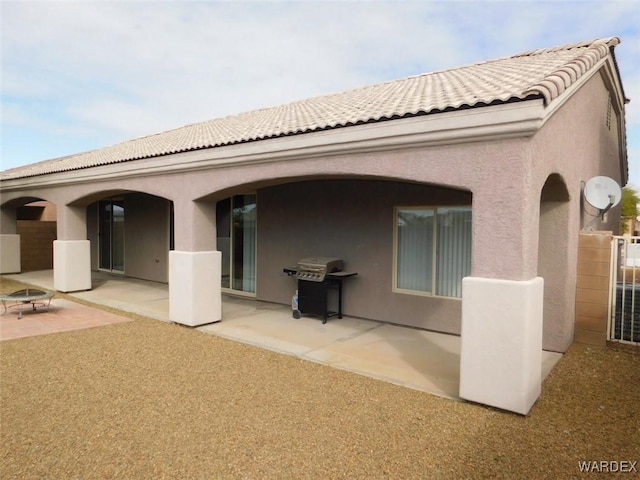 rear view of house with a tiled roof, a patio area, and stucco siding