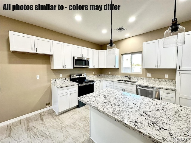 kitchen featuring light stone counters, pendant lighting, stainless steel appliances, white cabinetry, and a sink