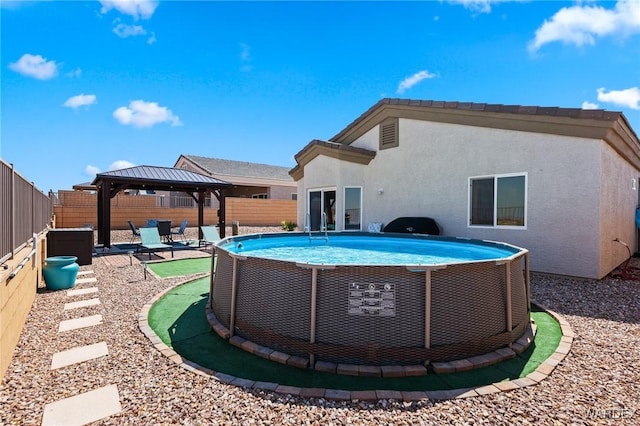 back of property featuring a gazebo, a fenced backyard, a fenced in pool, and stucco siding