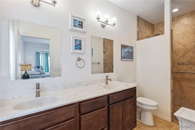 ensuite bathroom with double vanity, connected bathroom, a sink, and walk in shower