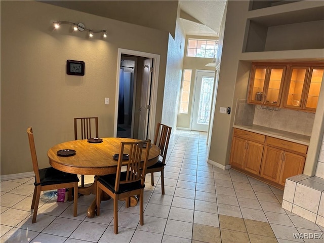 dining area featuring light tile patterned flooring, vaulted ceiling, and baseboards
