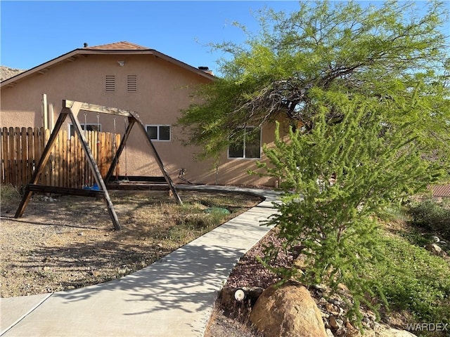 view of property exterior with stucco siding and fence