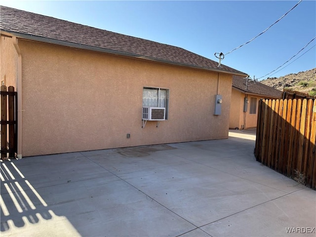 back of house with fence, stucco siding, and roof with shingles