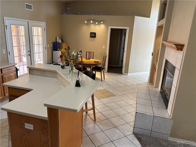 kitchen with light tile patterned flooring, visible vents, a kitchen island, and light countertops
